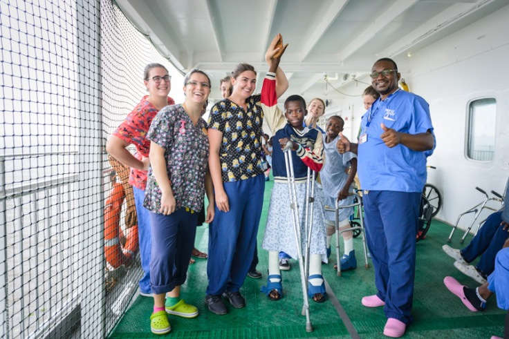 Ortho patient Ulrich showing how tall he is now with happy nurses around